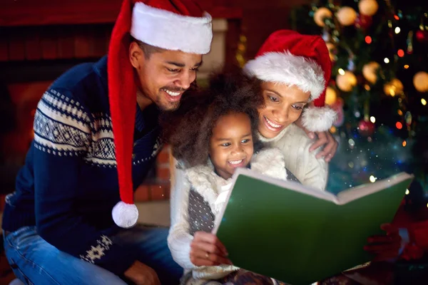 Nice black kid with parents look at new book — Stock Photo, Image