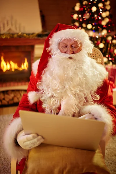 Рождественский отец в своей гостиной с ноутбуком — стоковое фото