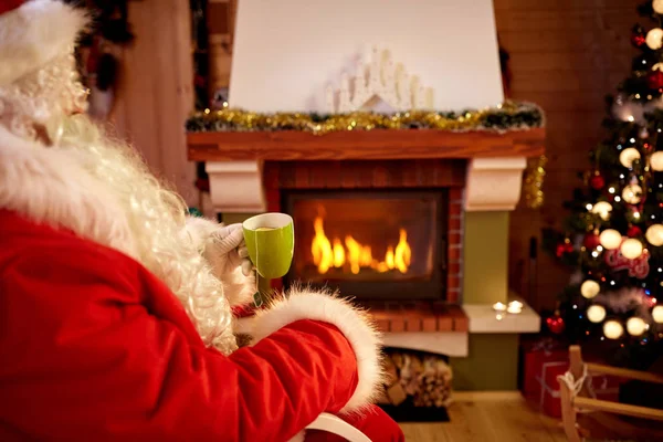 Santa Claus drinken tee in de buurt van open haard — Stockfoto