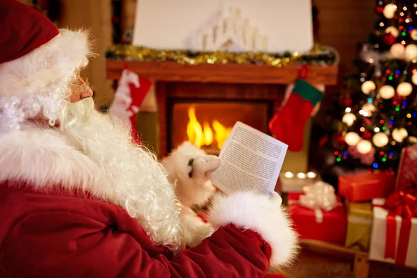 Santa Claus sentado y leyendo los deseos de los niños para x-mas — Foto de Stock