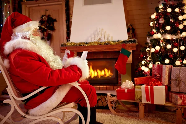 Weihnachtsmann im Zimmer neben dem Kamin las Wunschliste für die Taufe — Stockfoto