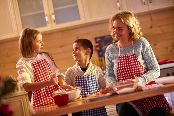 Niños felices horneando galletas con la madre en casa — Foto de Stock