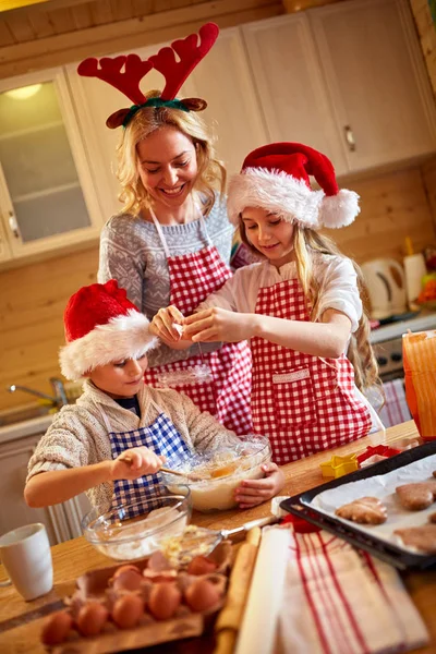 Mosolygó gyermek és anya otthon karácsonyi süti sütés — Stock Fotó
