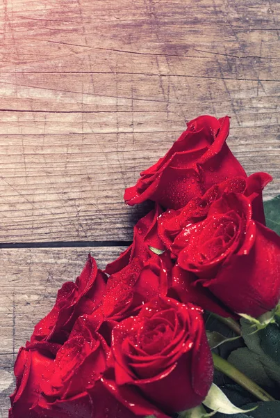 Hintergrund mit roten Rosen über Holztisch — Stockfoto
