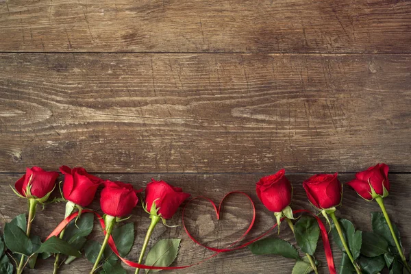 Close up on roses over wooden table with ribbon heart — Stock Photo, Image