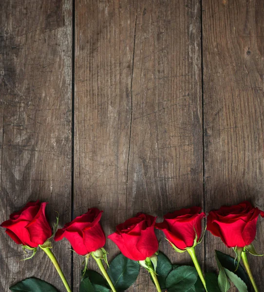 Strauß roter Rosen auf dunklem Holzgrund — Stockfoto