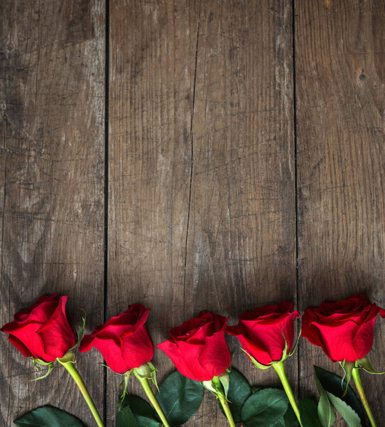 Аромат красных роз на темном деревянном фоне
