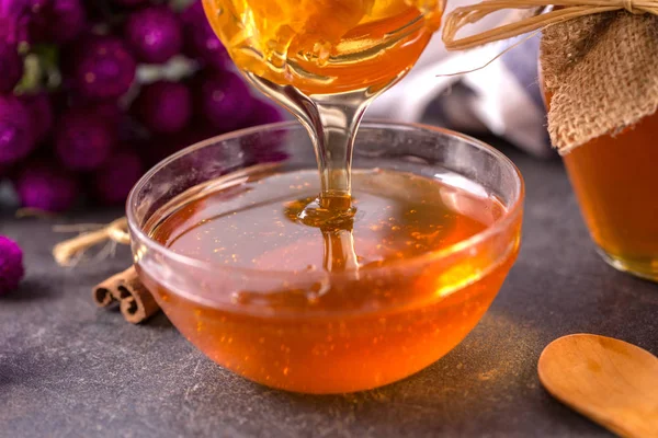 Honey dripping in glass bowl on table close up — Stock Photo, Image