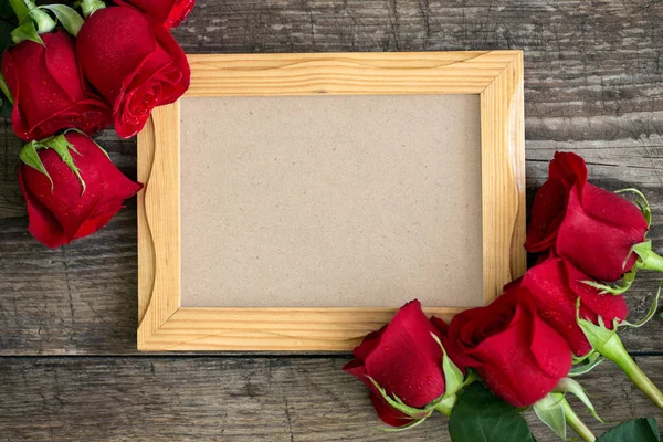 Moldura da foto e rosas vermelhas no fundo de madeira — Fotografia de Stock