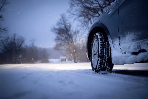 Автомобиль и падающий снег зимой на лесной дороге — стоковое фото