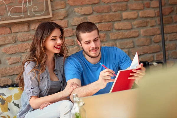 Mannelijke en vrouwelijke studenten schrijven en leren in café — Stockfoto