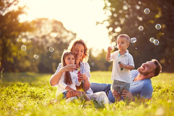 Сім'я з дітьми дме мильні бульбашки — стокове фото