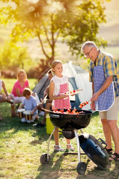 Smilende bestefar og barnebarn griller grillmat – stockfoto