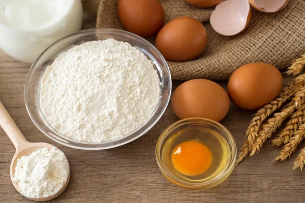 Eggs, flour and milk on wooden background — Stock Photo, Image