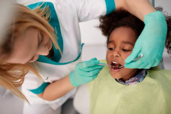 Dentista hembra reparación diente a negro niño — Foto de Stock