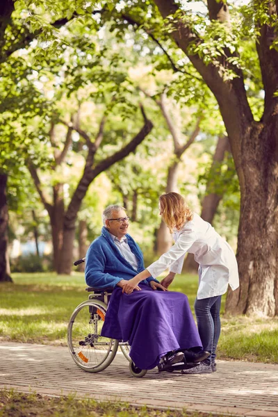 Enfermera masculina ayudando a hombre mayor en silla de ruedas —  Fotos de Stock