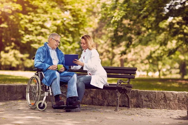 Infirmière parlant avec le patient en fauteuil roulant vérifier l'histoire — Photo