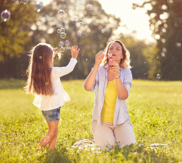 Девушка гоняется за мыльными пузырями в парке — стоковое фото