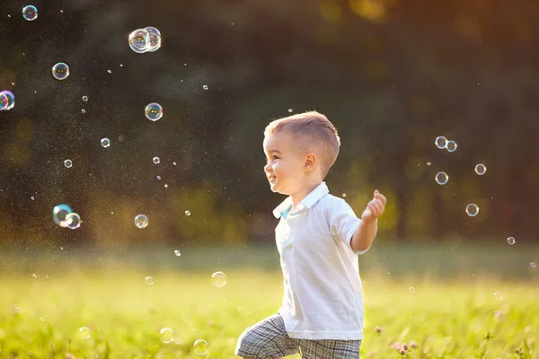 Niño varón persecución jabón burbujas — Foto de Stock