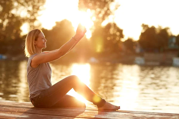 Frau macht Selfie am Fluss bei Sonnenuntergang — Stockfoto