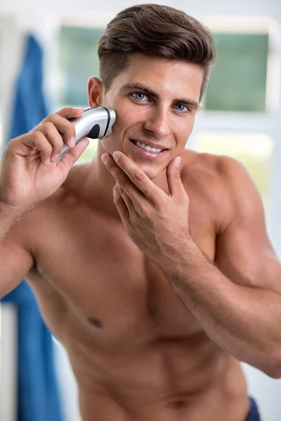 Young men front of  mirror shaving with electric shaver — Stock Photo, Image