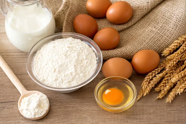 Eggs, flour and baking ingredients on a wooden table — Stock Photo, Image
