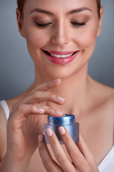 Smiling woman using cream — Stock Photo, Image