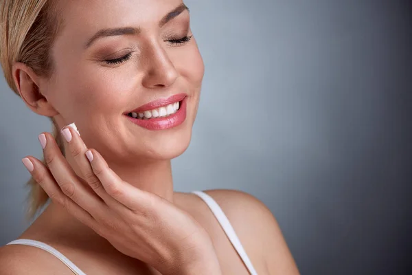 Mujer de mediana edad disfrutando en crema facial —  Fotos de Stock