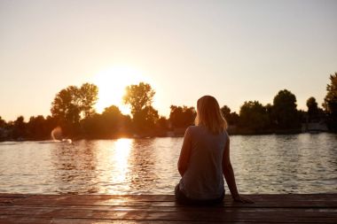 Oturan ve gün batımı arıyorsunuz geri gelen kadın