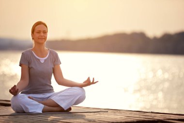 Kadın yoga poz oturan dock cihazı üzerindeki