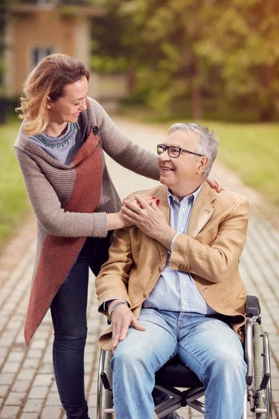 Jeune femme avec son père handicapé en fauteuil roulant dans le parc — Photo