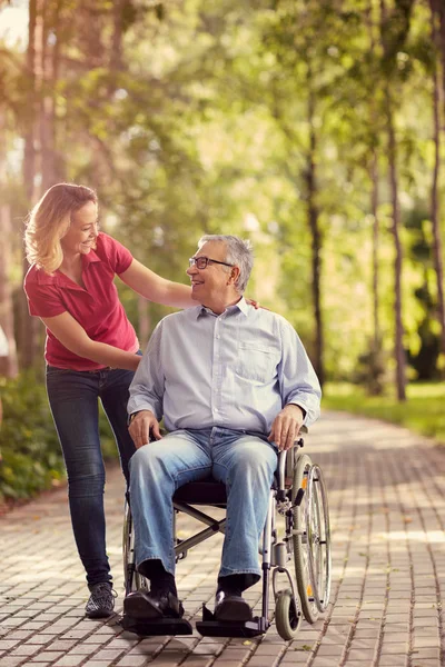 Lachende jonge vrouw met haar handicap vader in rolstoel — Stockfoto