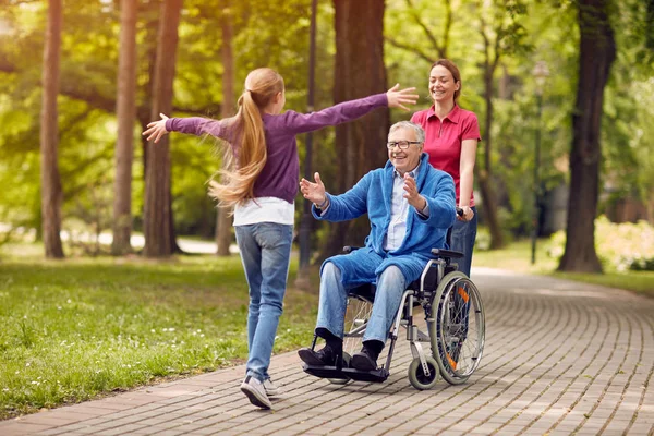 Behinderter Großvater im Rollstuhl begrüßt seine Enkelin — Stockfoto