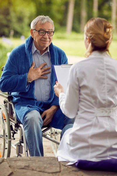 Homme âgé en fauteuil roulant qui ne se sent pas bien avec l'infirmière — Photo