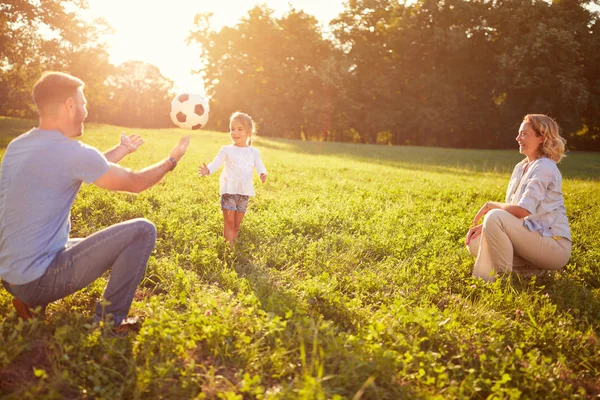 Родители с дочерью играют в мяч в парке — стоковое фото