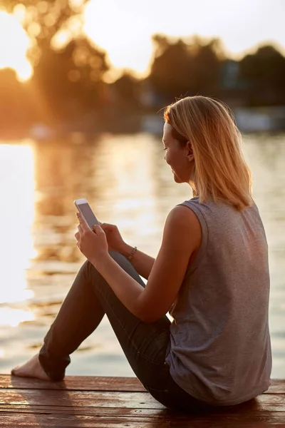 Vrouw met cellphone ontspannen in de buurt van water — Stockfoto