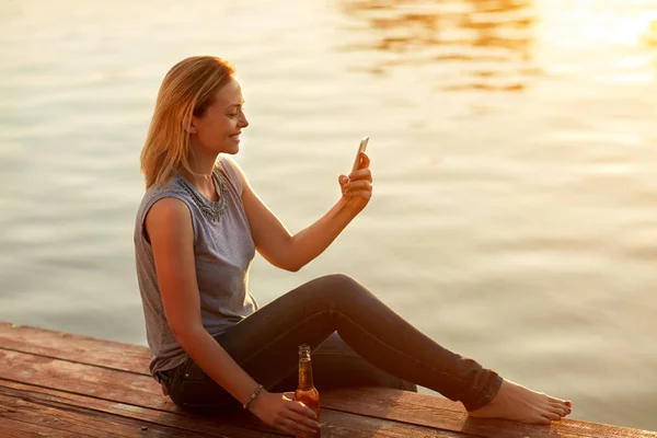 Donna rilassarsi vicino all'acqua al tramonto — Foto Stock