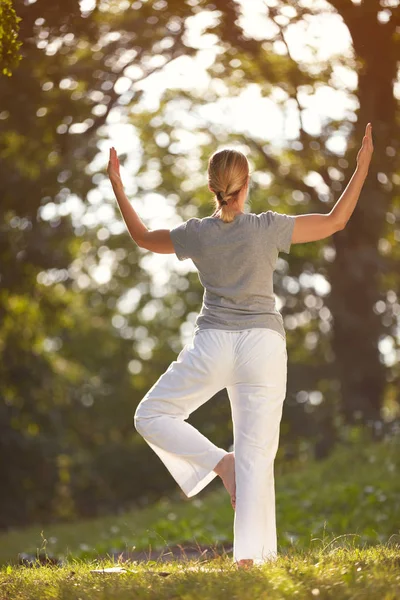 Kvinne som praktiserer yoga i parken – stockfoto