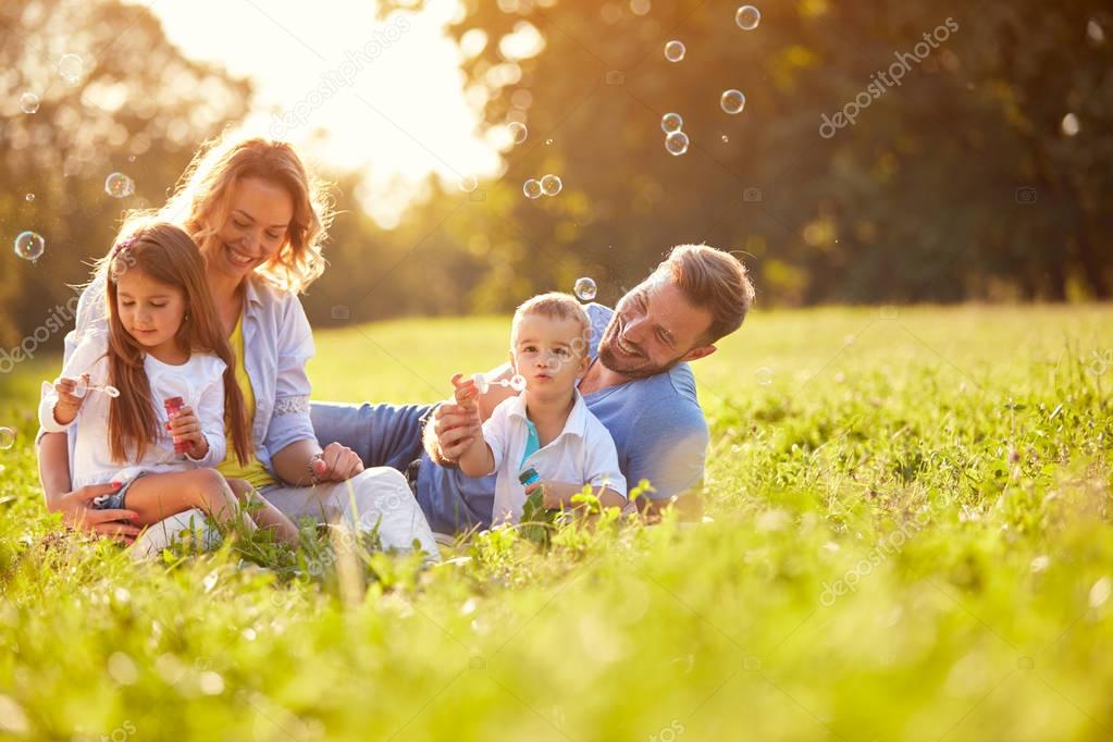 Children in green nature make soap bubble on summer