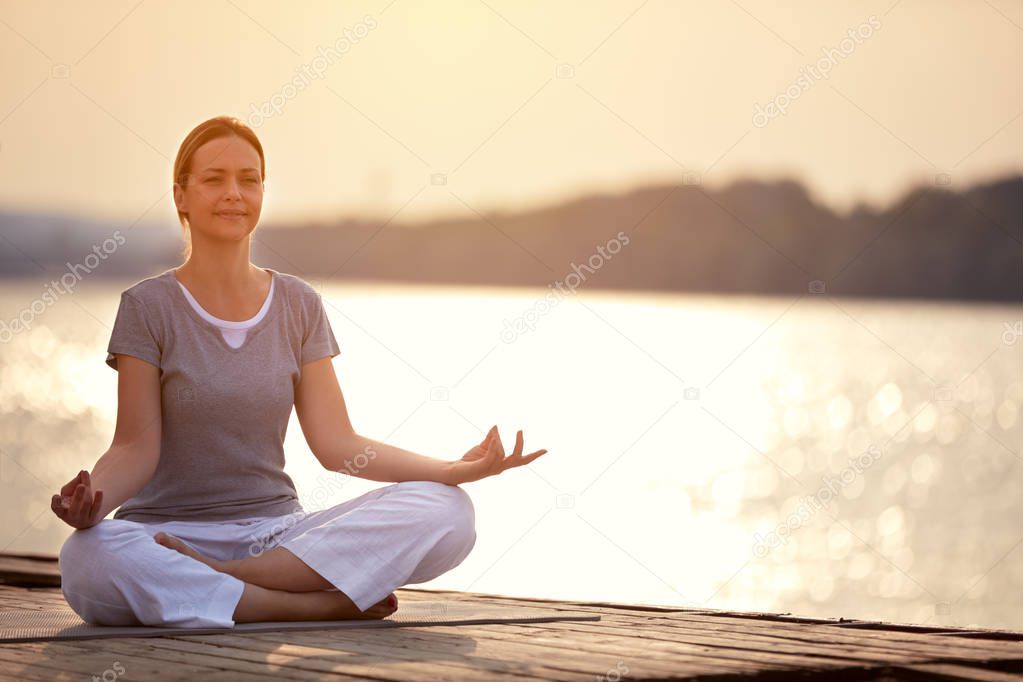 Woman on dock sitting in yoga pose