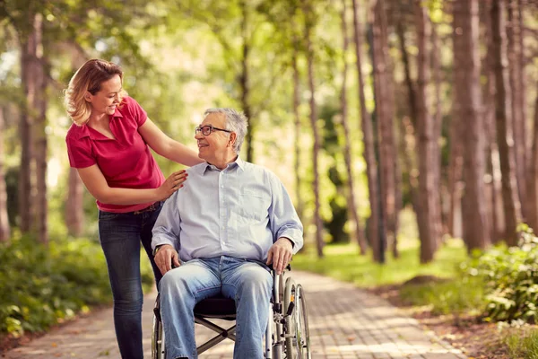 Smiling woman with her disabled father in wheelchair — Stock Photo, Image