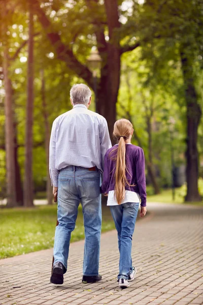 Menina e seu avô de mãos dadas na caminhada — Fotografia de Stock