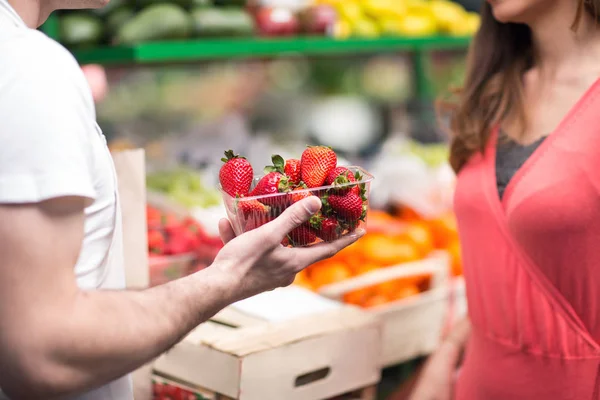 Verkäufer hält Erdbeeren auf Wochenmarkt — Stockfoto