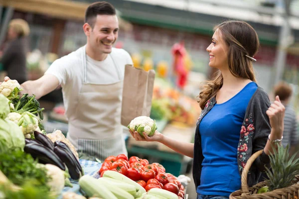 Женщина улыбается и держит цветную капусту на рынке — стоковое фото