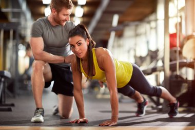 Girl doing pushups with trainer's helps clipart