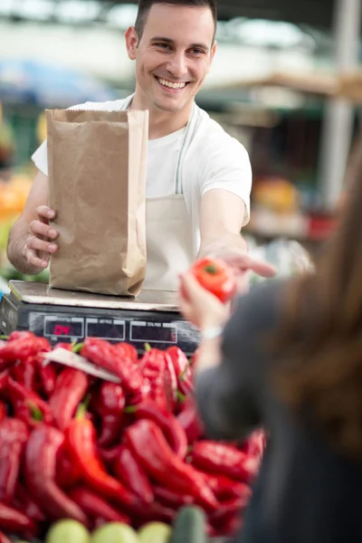 Young salesman measuring vegetables customer in grocery store — Stock Photo, Image