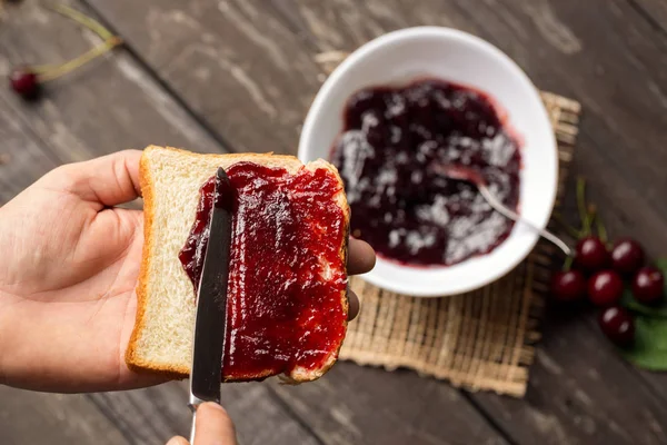 Man is preparing breakfast and spreading marmalade on toast — Stock Photo, Image