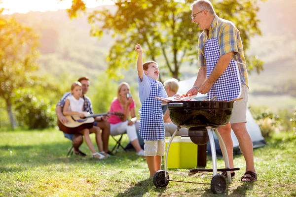 Happy grandfather and grandson making barbecue — Stock Photo, Image