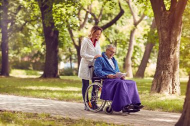 Yaşlı adam kitap okumak tekerlekli sandalyede hemşire Park ile