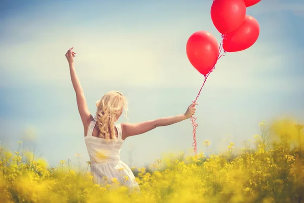 Chica divirtiéndose con globos en prado de flores — Foto de Stock